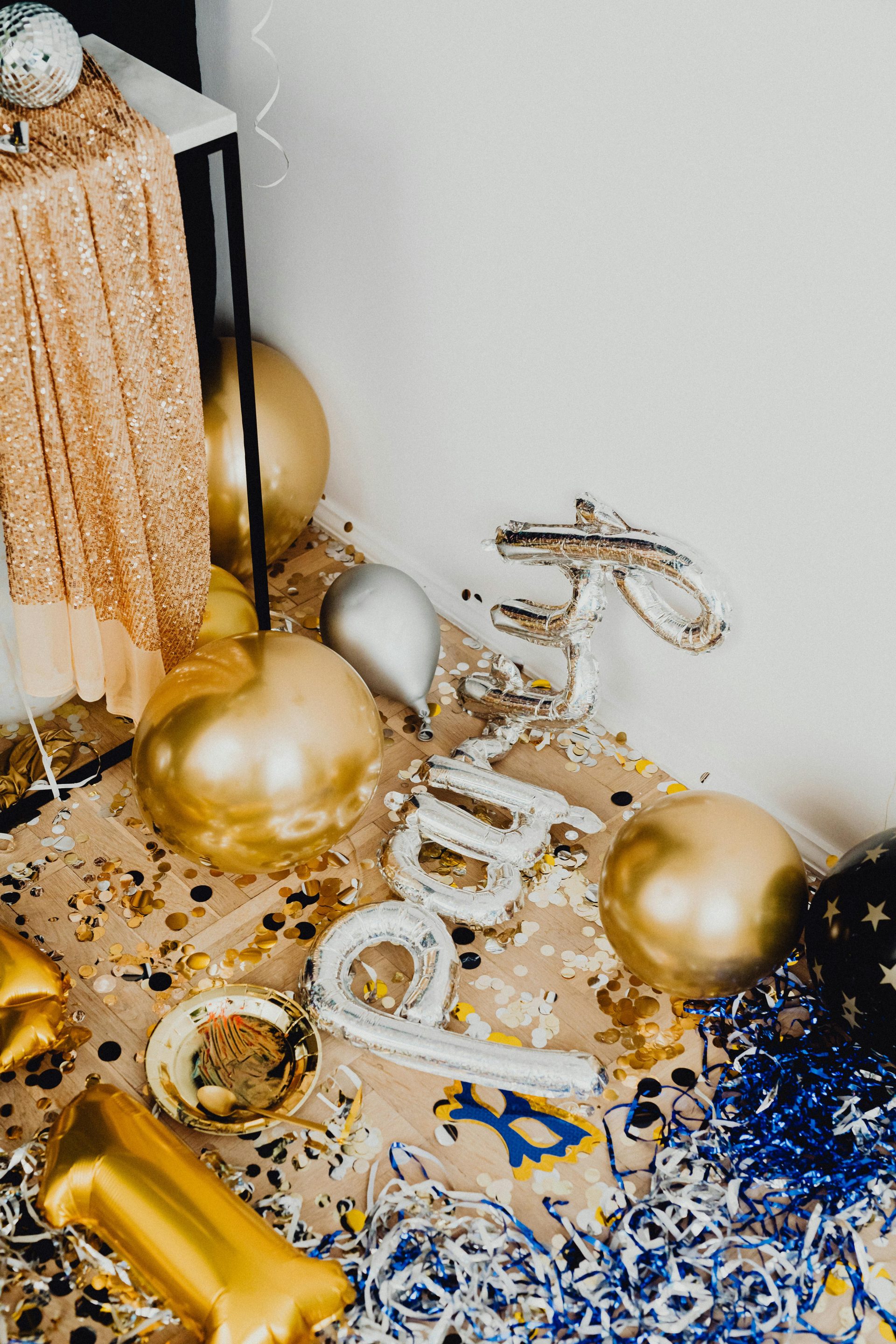 Festive gold and silver balloons with confetti creating a celebratory New Year's Eve atmosphere.